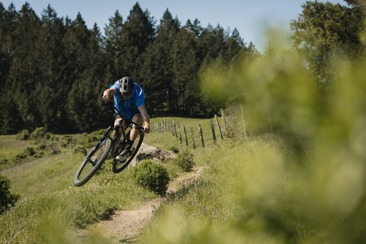 man riding a single track trail, on a rift zone mountain bike in the sunshine 