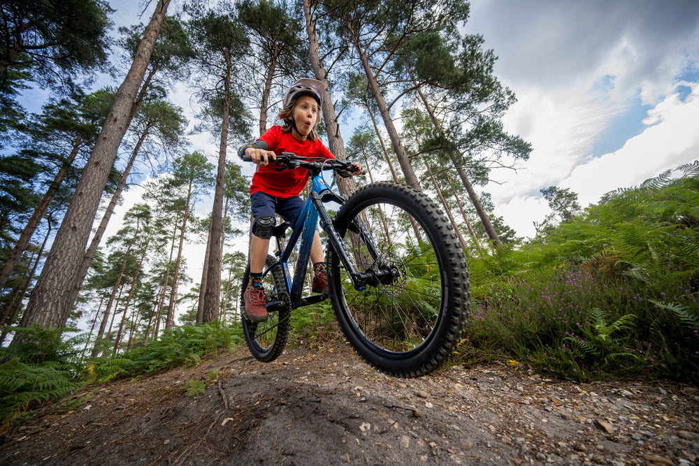 boy jumps blue bike and pulls face