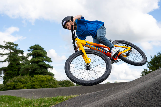 Kid jumps yellow bike out of berm