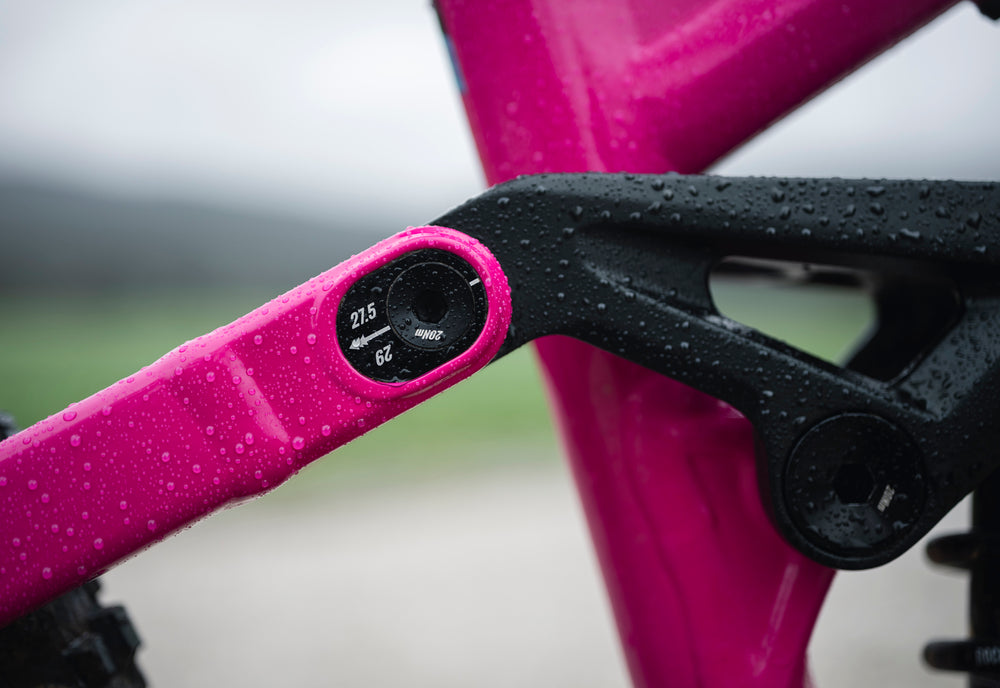 Close-up of a pink bicycle frame with black components and measurement markings.