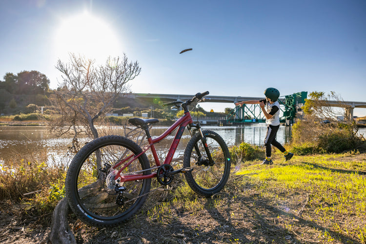 Boy throws a stick in the water during a bike ride