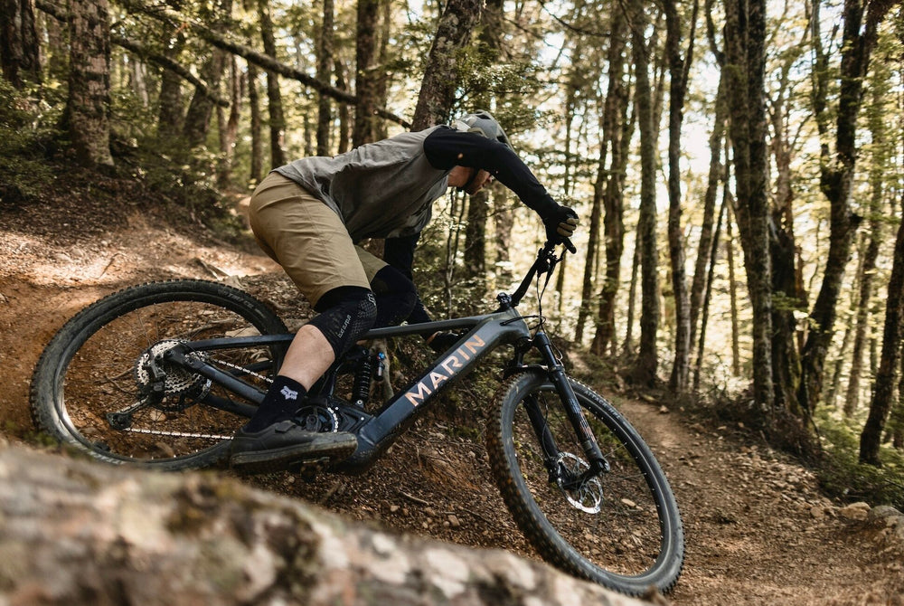 An image of a Marin Bikes Alpine Trail E2 electric mountain bike ridden by a male mountain biker around a corner in a dense forest