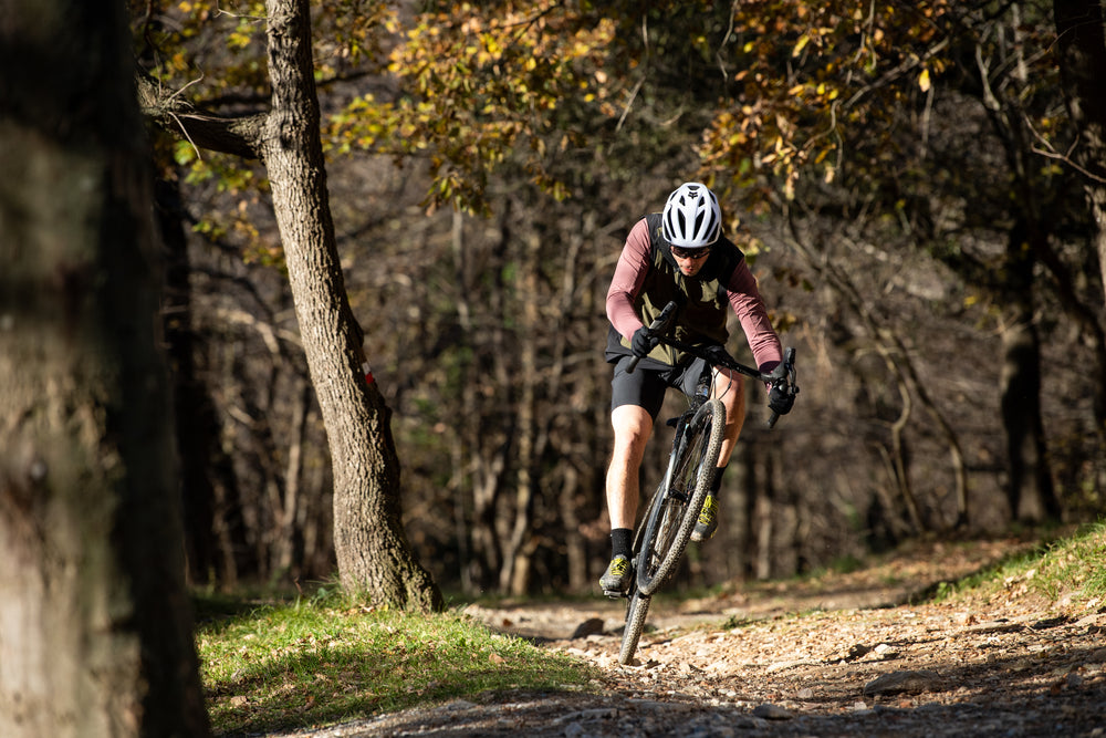 Man doing a wheelie on a drop bar bike on a woodland trial