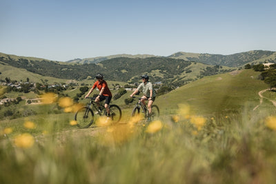 Couple ride bikes along a gravel track in the mountains