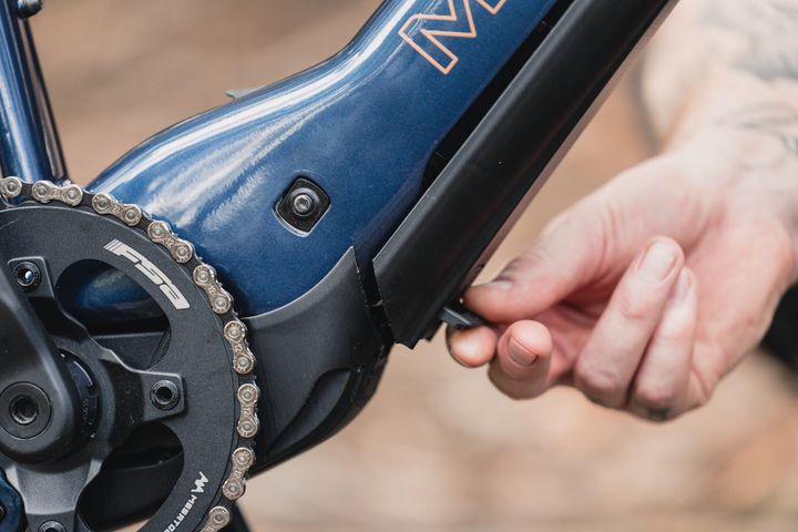 Close-up of a person adjusting a bicycle chain on a blue frame.