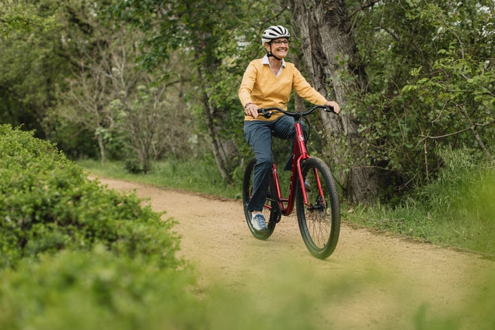 Woman rides a bike along a woodland track