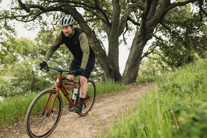 Man rides along a gravel track in woodland