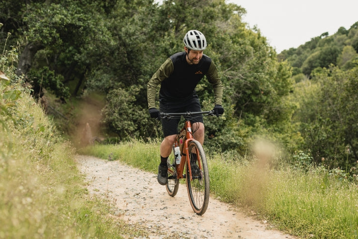 Man rides along a gravel track in woodland